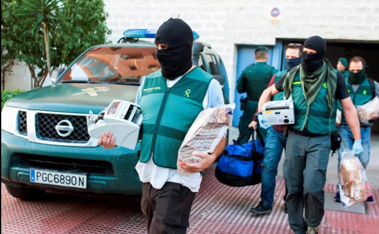 Agentes de la Guardia Civil sacan varias bolsas y ordenadores de una vivienda de Málaga capital, durante uno de los once registros simultáneos realizados en la operación denominada «Maskoke»