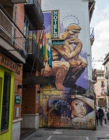 Imagen secundaria 2 - El Niño de las PInturas contempla su icónico mural en la Cuesta del Realejo, que necesita una restauración. El gato gordo y naranja se puede ver con Lorca en Manhattan. La Niña de las PInturas ha desaparecido ya, solo queda el pensador gigante en la calle Molinos.