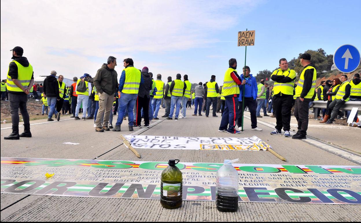 Garrafas de aceite en la calzada ante varias pancartas. 