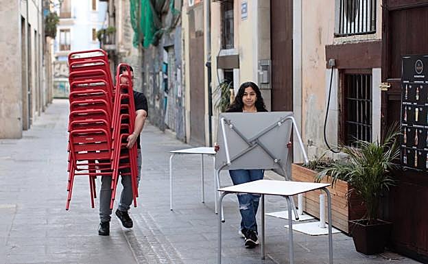 Trabajadores de un bar retiran una terraza tras ordenarse el cierre de espacios públicos en Valencia 
