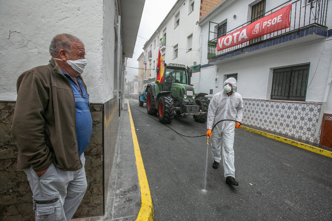 Un vecino de Deifontes observa el paso de la brigada agrícola de desinfección por las calles del pueblo. 