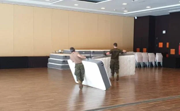 Los miembros del ejército transportan colchones que no se utilizarán a uno de los salones.