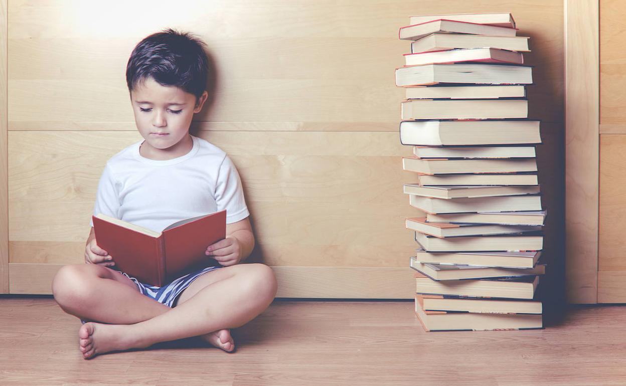 Un niño estudia junto a un montón de libros