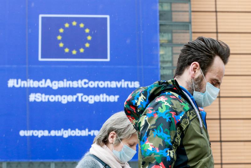 Dos personas pasan por delante del del cartel con el mensaje de unidad contra el coronavirus que luce en la sede de la Comisión Europea en Bruselas. 