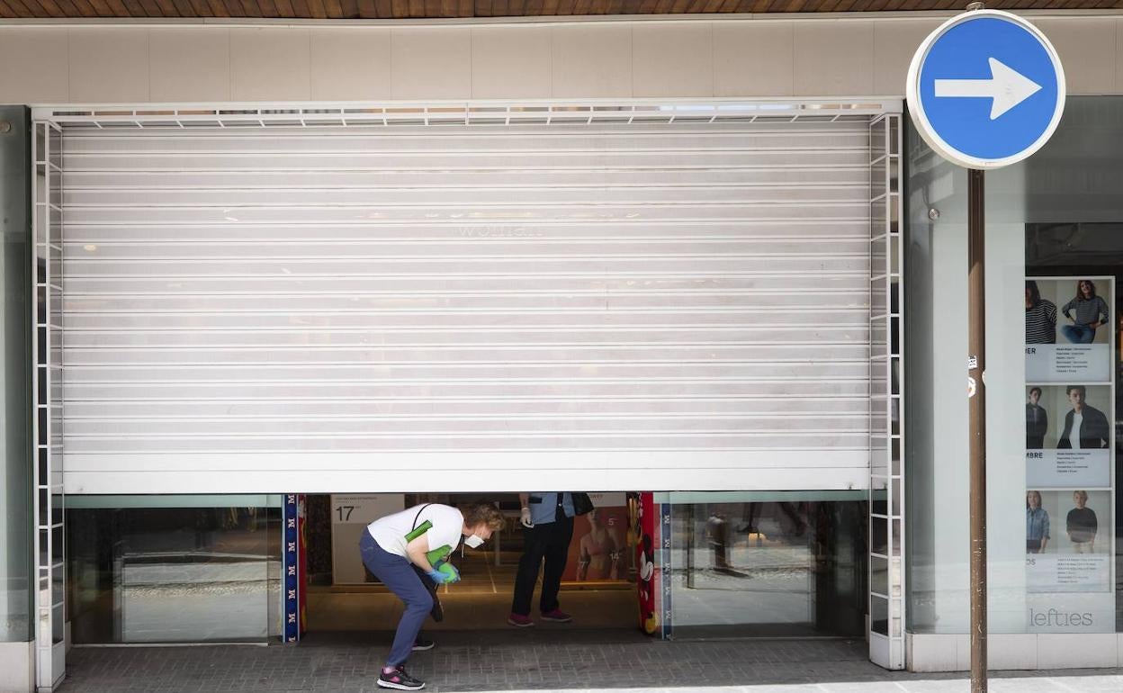 Un negocio con la persiana medio bajada preparando la fase de desescalada. 
