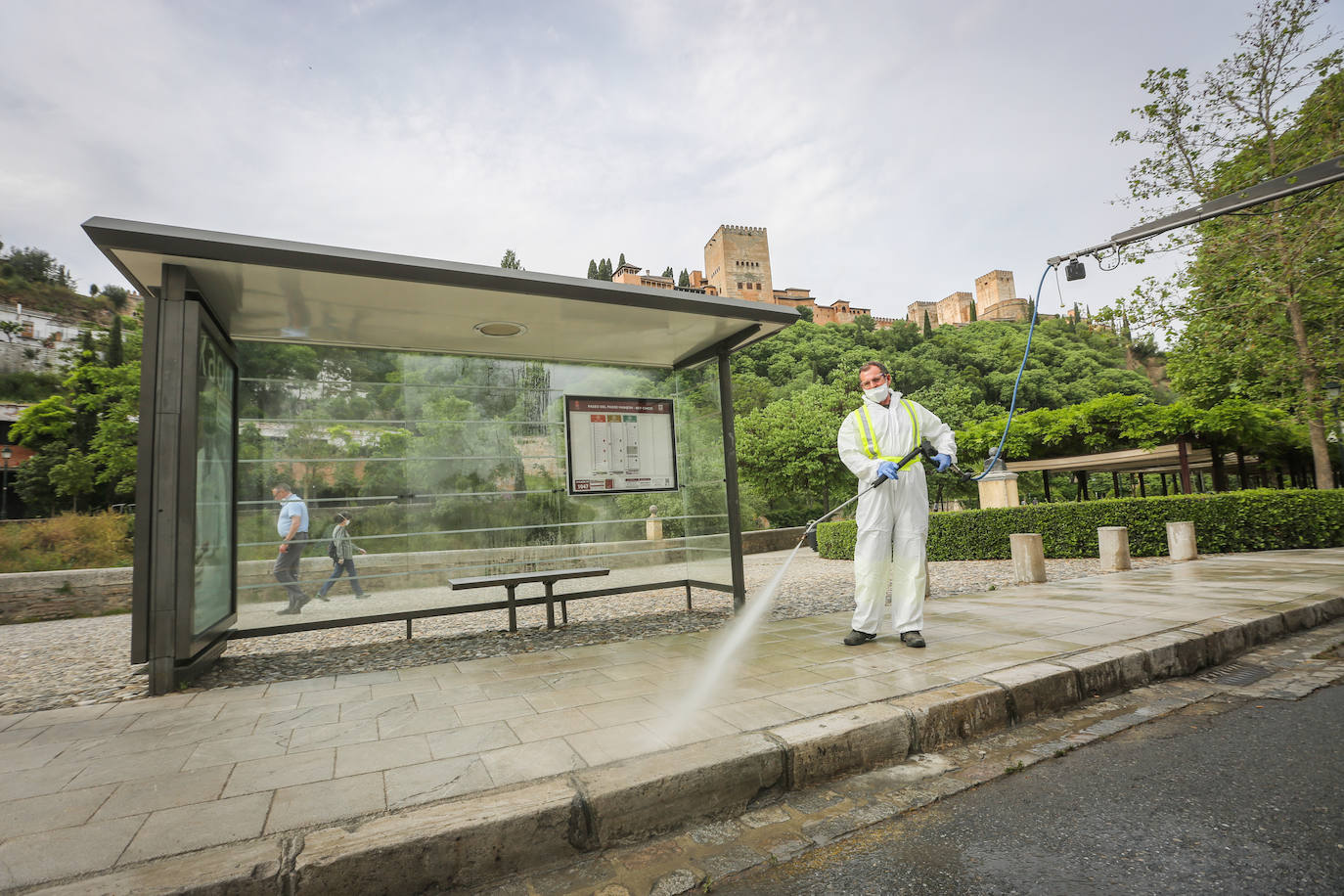 Operarios de Inagra desinfectan el Paseo de los Tristes, con la Alhambra como telón de fondo.