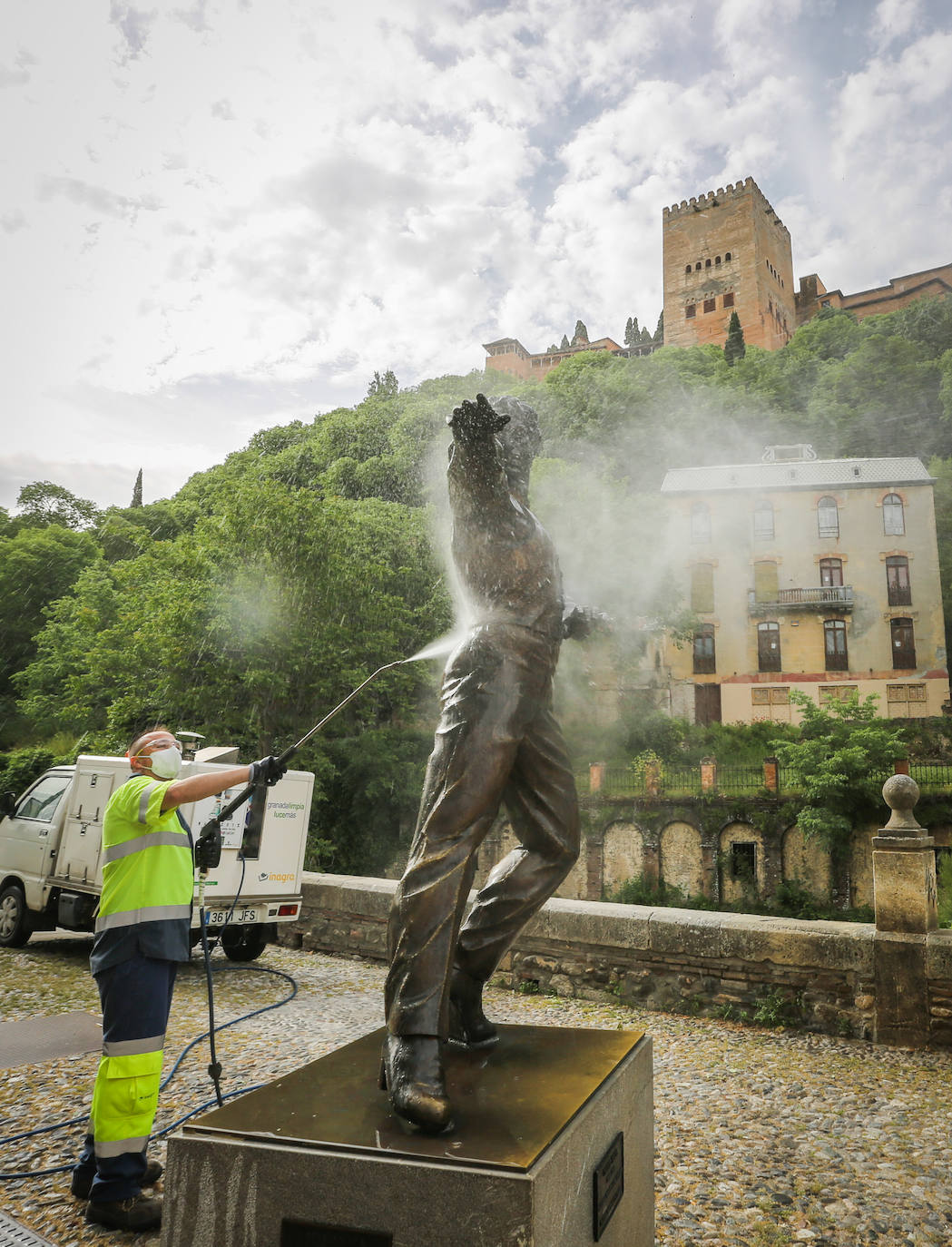 Operarios de Inagra desinfectan el Paseo de los Tristes, con la Alhambra como telón de fondo.