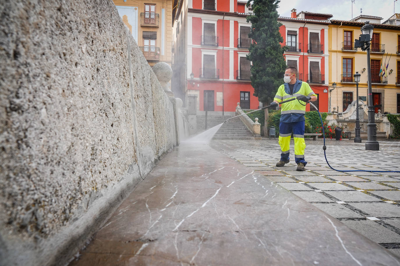 Operarios de Inagra desinfectan el Paseo de los Tristes, con la Alhambra como telón de fondo.