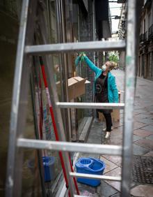 Imagen secundaria 2 - Arriba, José Manuel levanta la persiana como volverá a hacerlo mañana. Debajo, Gabriel con la fregona en Calzados Rosa Maciá, de Acera del Darro, y Toñi limpiando escaparates en Zacatín.