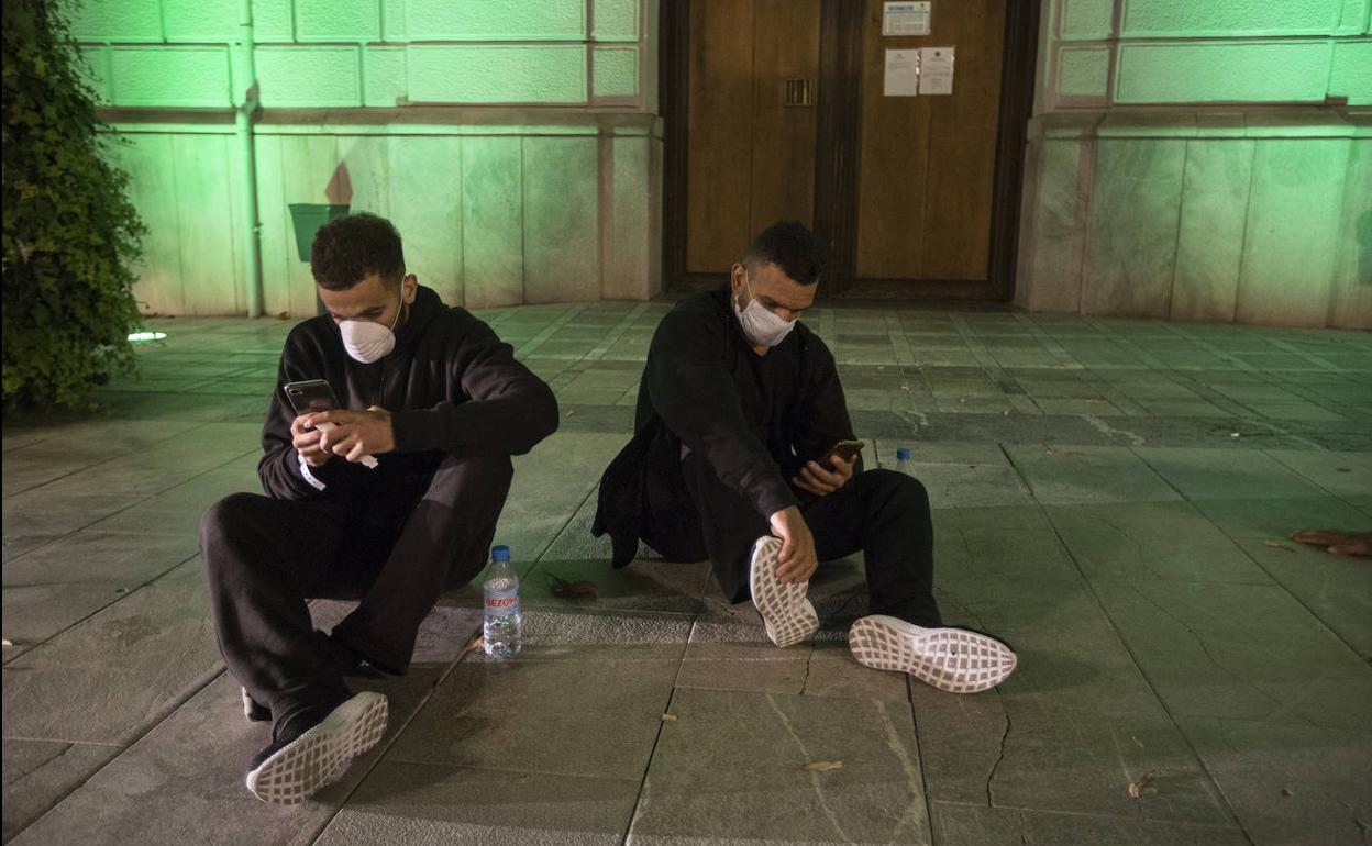 Dos de los jóvenes miran sus móviles en la plaza del Carmen, en la noche de este domingo. 