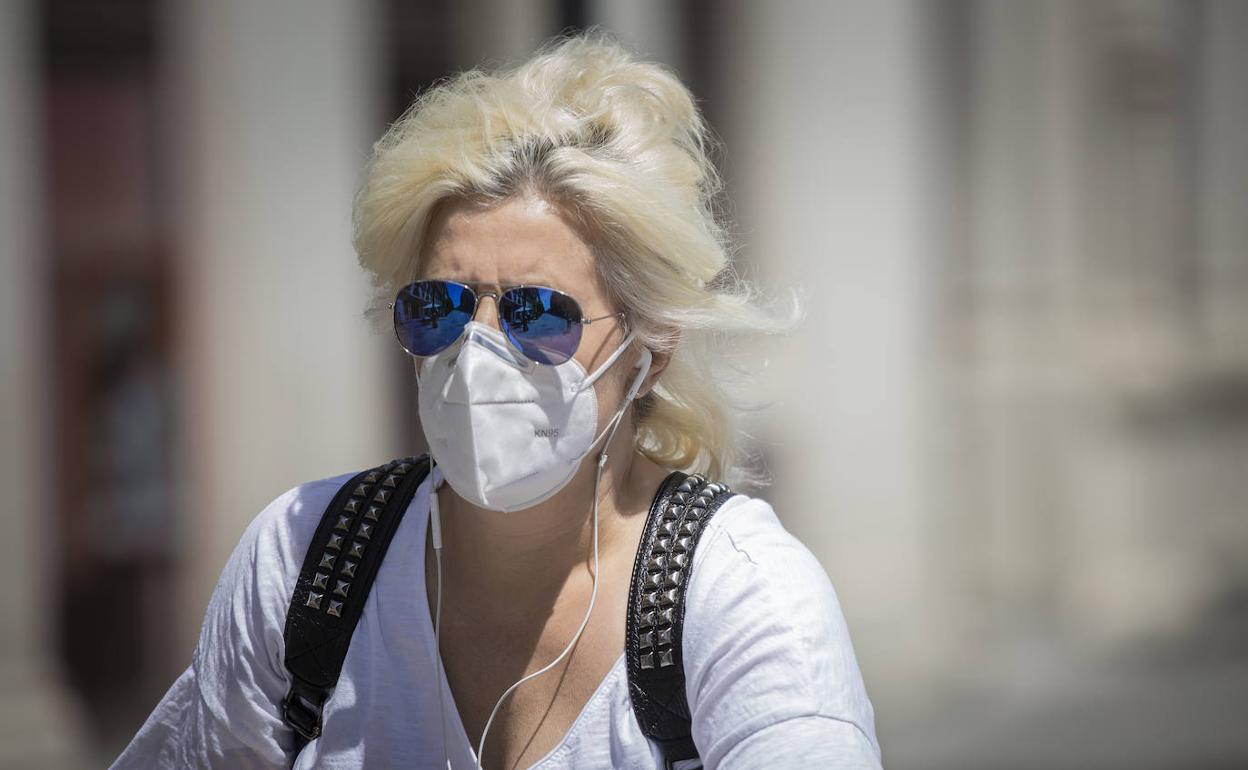 una señora camina con su mascarilla. 