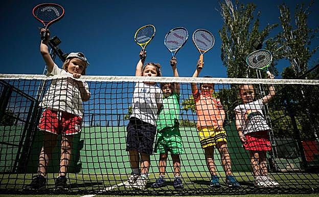 Unos niños que se están formando se asoman a la red de la pista de pádel, donde hacen 'minitenis' con sus raquetas. 