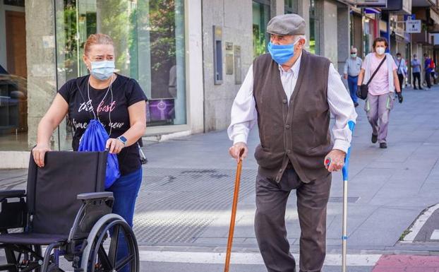 Un anciano pasea con mascarilla acompañado de una mujer.