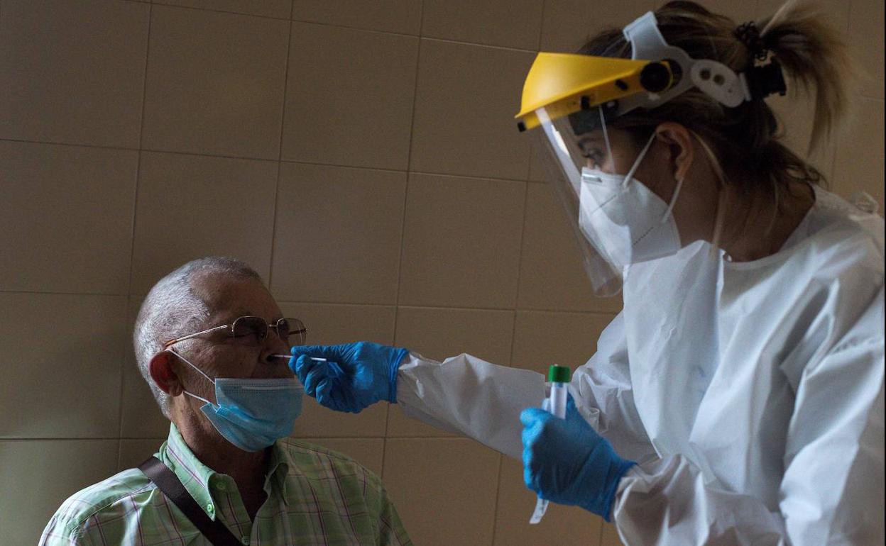 Una sanitaria realiza una prueba PCR a un paciente. 