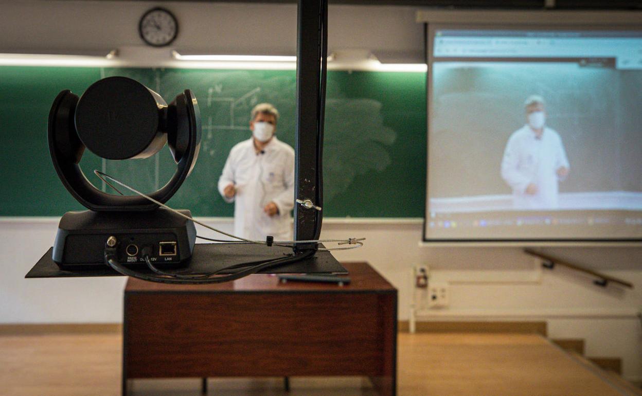 Un profesor de la Facultad de Ciencias, solo en el aula, imparte su clase virtual, enfocado por una cámara. 