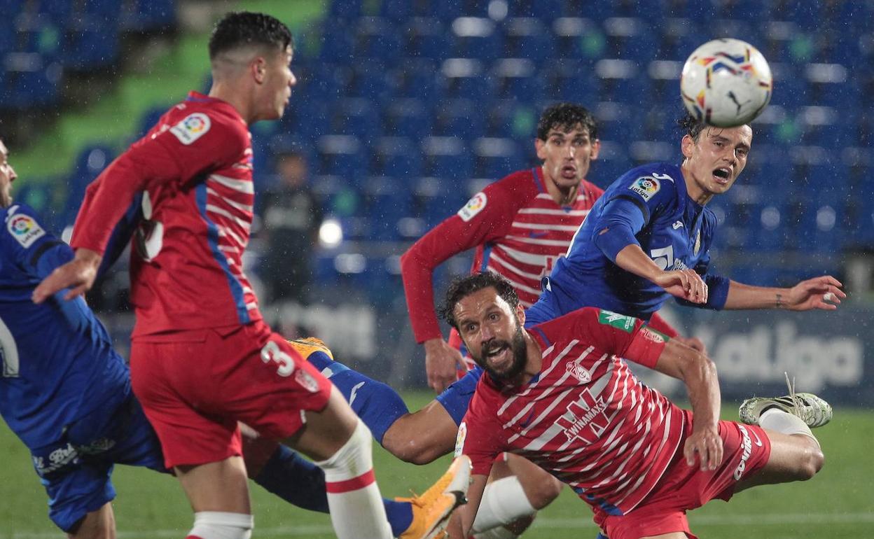 Los futbolistas del Getafe y el Granada pelean bajo la lluvia. 
