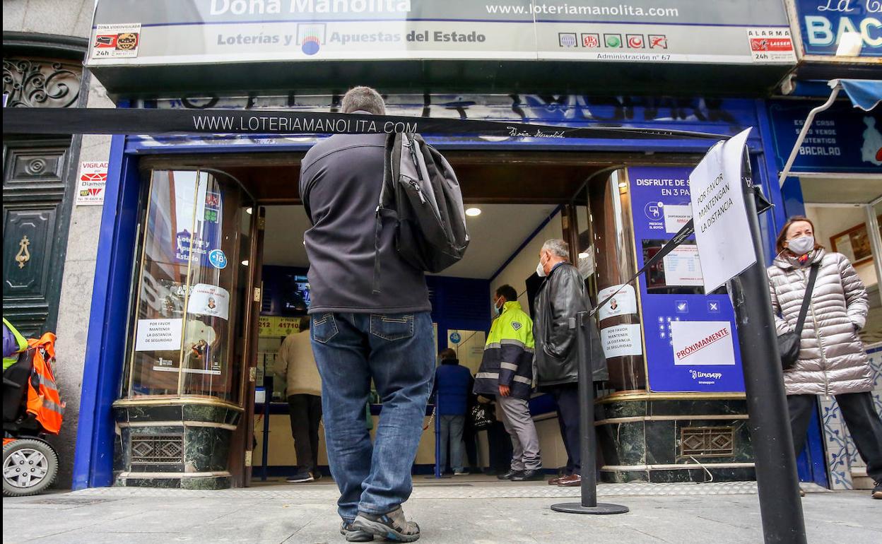 Varias personas hacen cola en las puertas de la administración de Doña Manolita, en Madrid. 