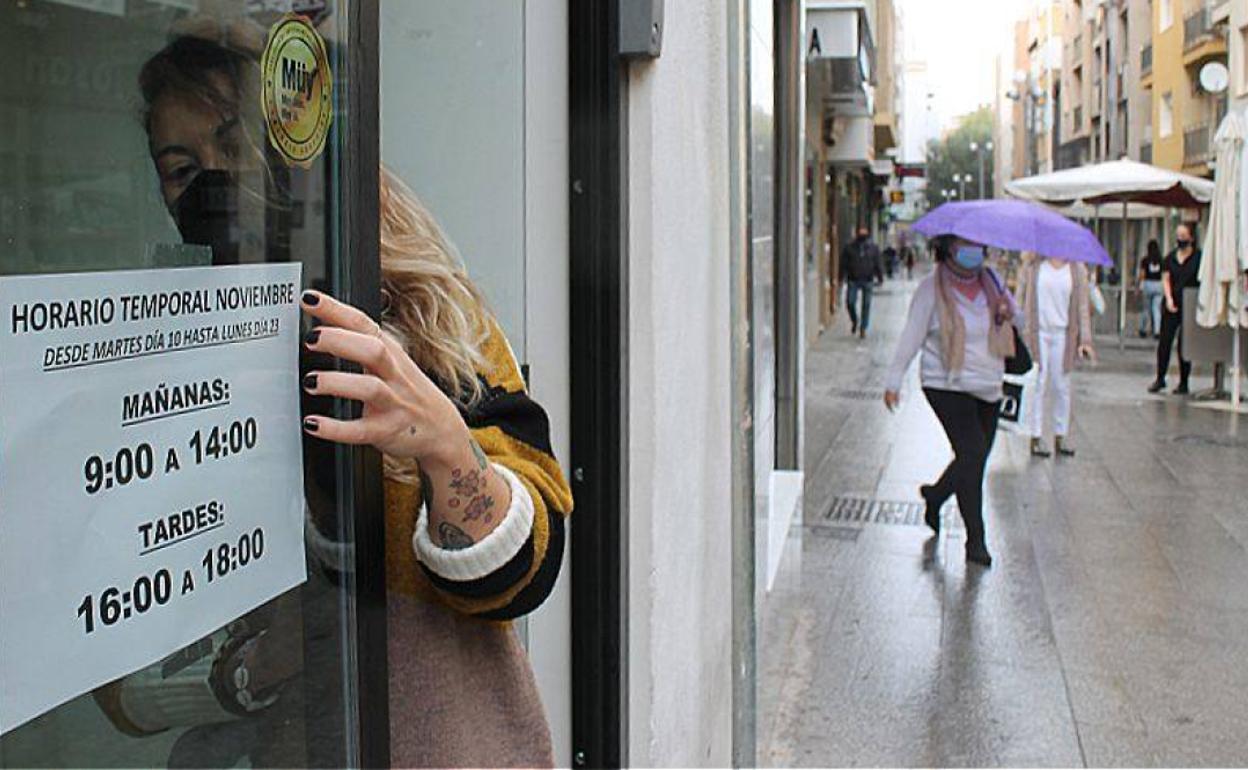 Sonia Rodríguez coloca un cartel con el nuevo horario este lunes en la tienda Nina de la calle San Clemente en Jaén capital. 
