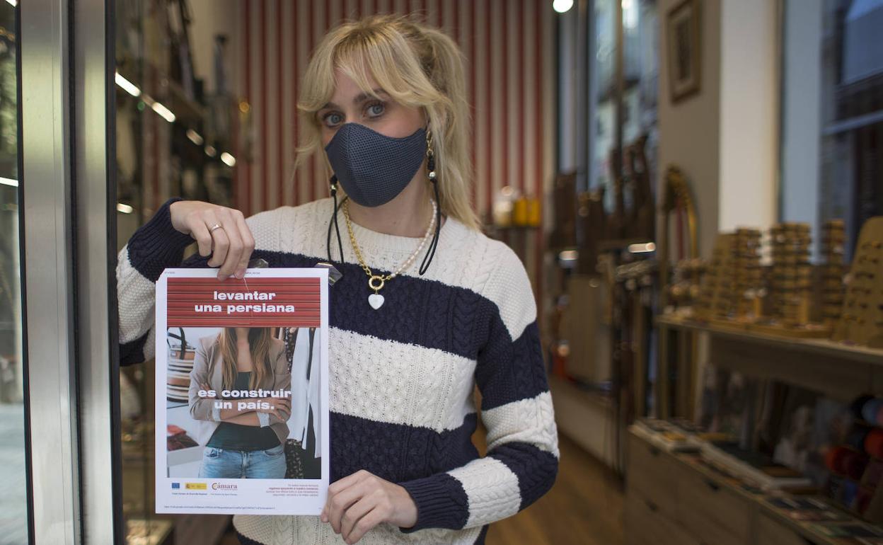 Mari Carmen muestra un cartel desde su tienda de complementos en la calle Mesones. 