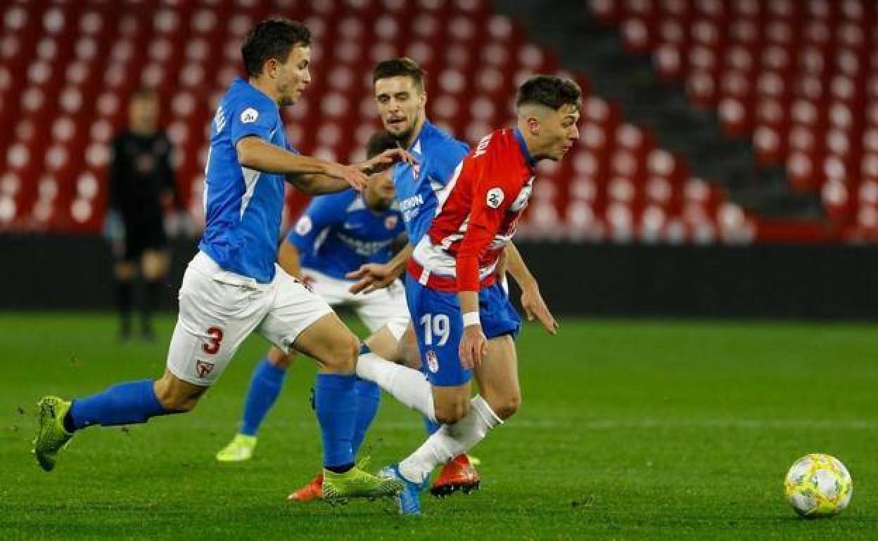 El granadino Antonio Aranda escapa al marcaje de dos futbolistas del Sevilla Atlético en el duelo del curso pasado, que se disputó en Los Cármenes. 