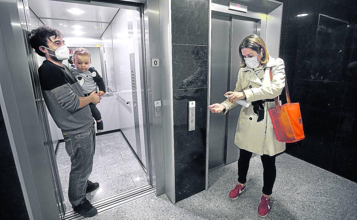 Una vecina se desinfecta antes de entrar al ascensor.