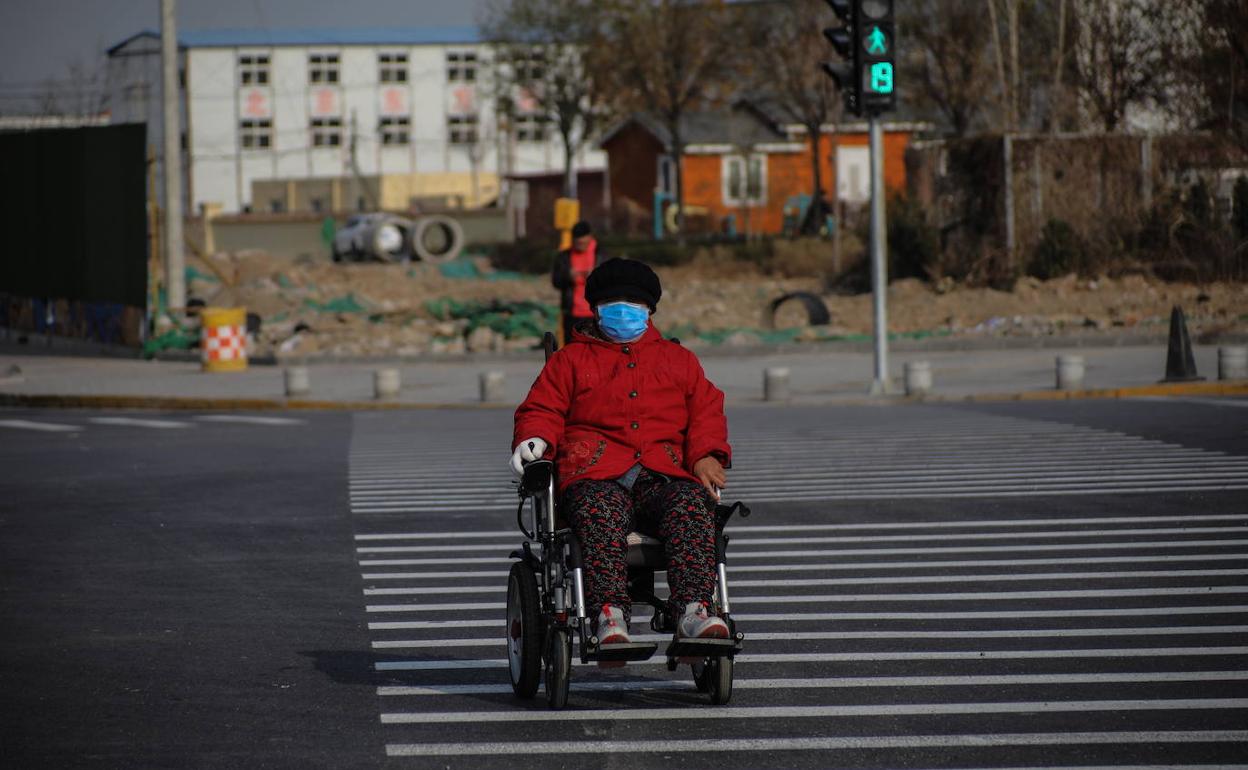 Una mujer en silla de ruedas cruza un paso de peatones en China. 