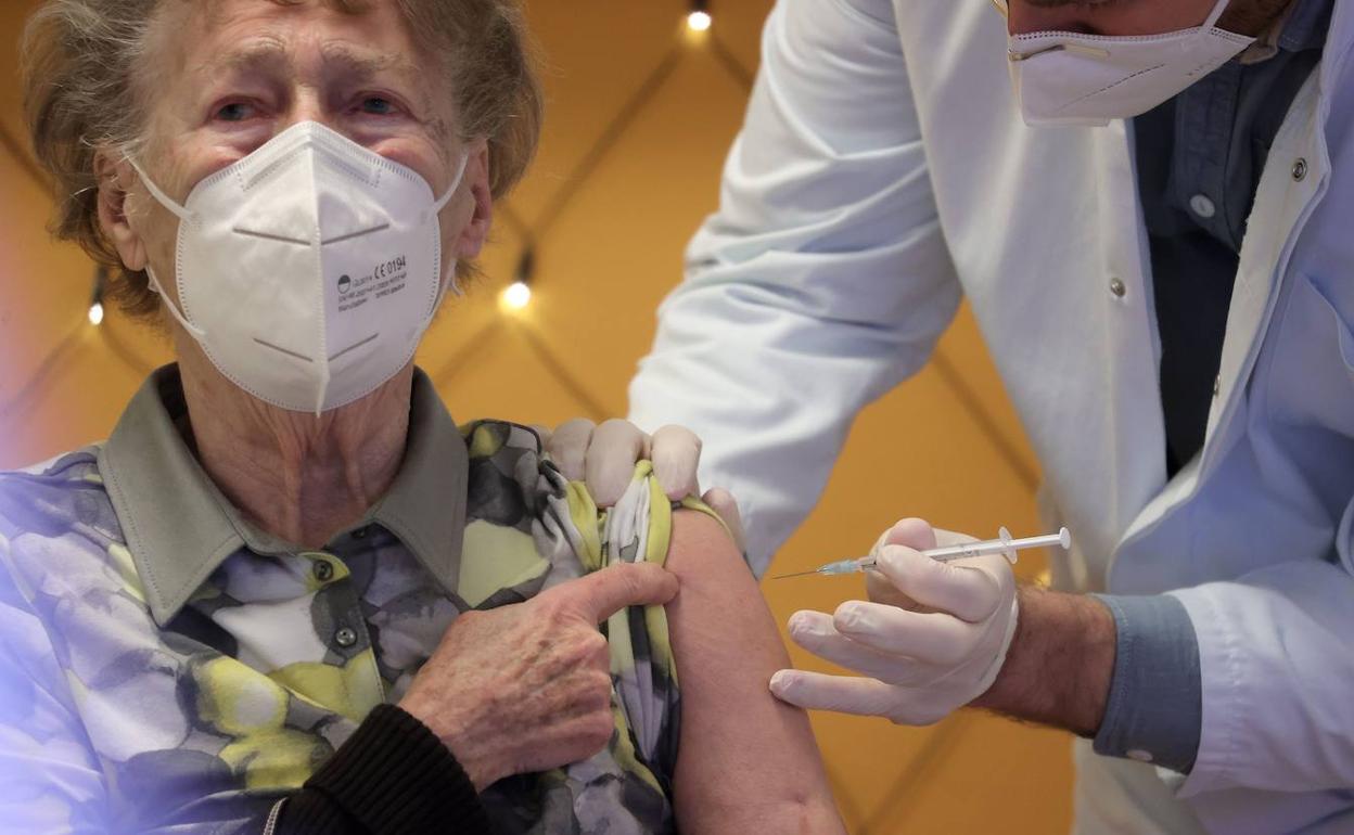 Un sanitario inocula la vacuna a una mujer mayor.