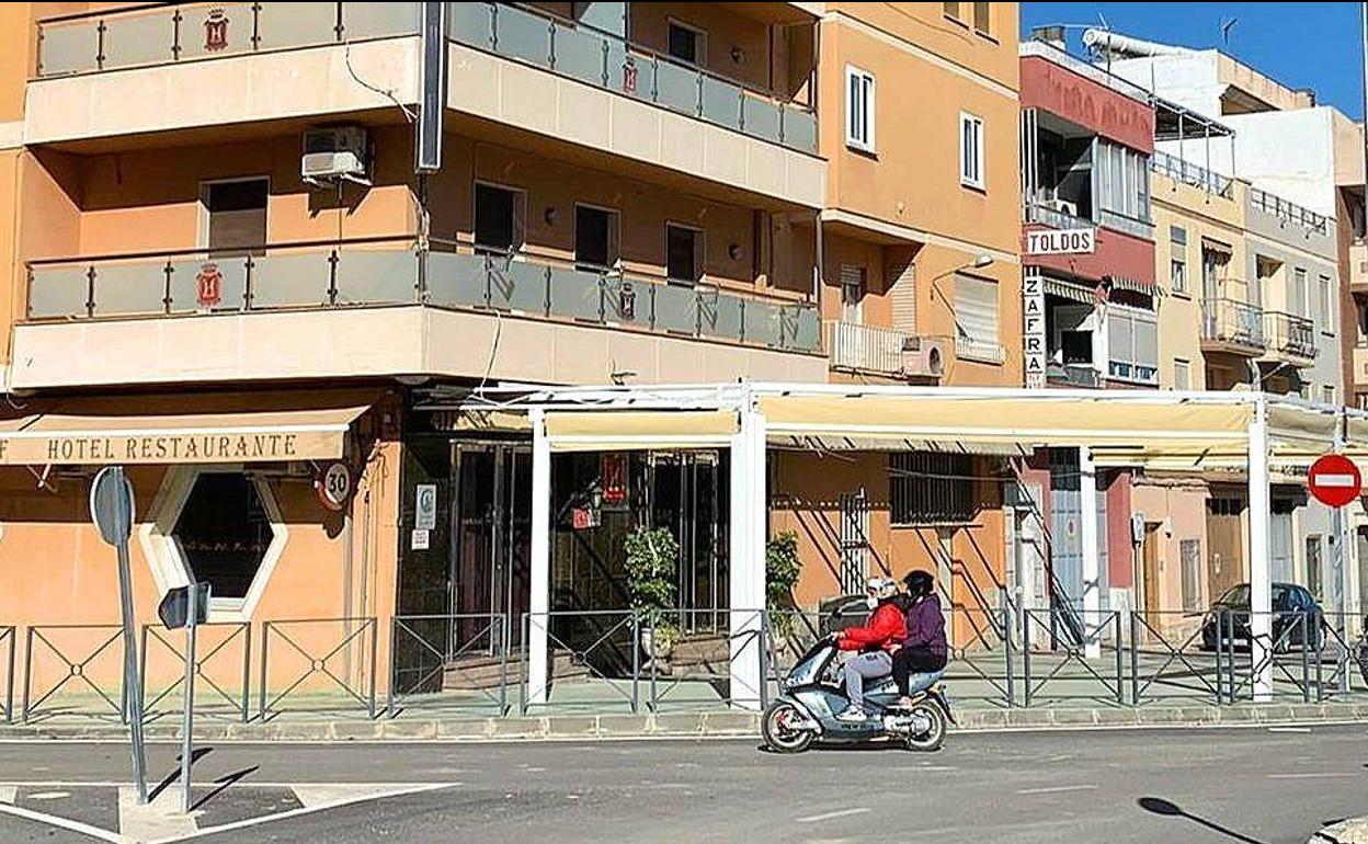 Un moto con dos personas con casco y mascarilla pasa por delante de uno de los hoteles más conocidos de Torredelcampo, con la terraza cerrada este domingo domingo al mediodía por las limitaciones. 