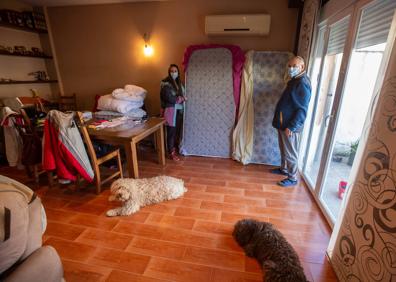 Imagen secundaria 1 - Julia y su padre muestran las rajas en la pared del salón de su vivienda, donde han bajado los colchones para dormir más seguros. Una vista de la calle Olivares de Atarfe, donde viven.