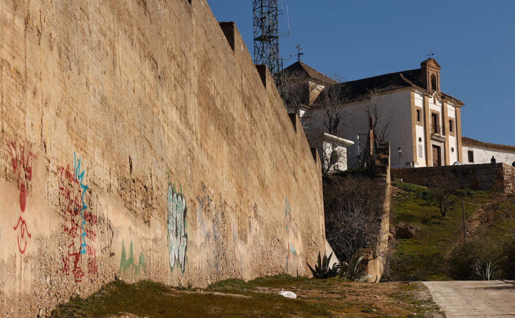 Al pie de la ermita, la muralla del siglo XIV, repleta de pintadas a lo largo de toda su extensión hasta el entorno de Fajalauza.