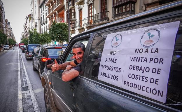 Uno de los participantes en la caravana de vehículos, a su paso por la Gran Vía, con carteles con sus peticiones en las ventanillas de la furgoneta. 