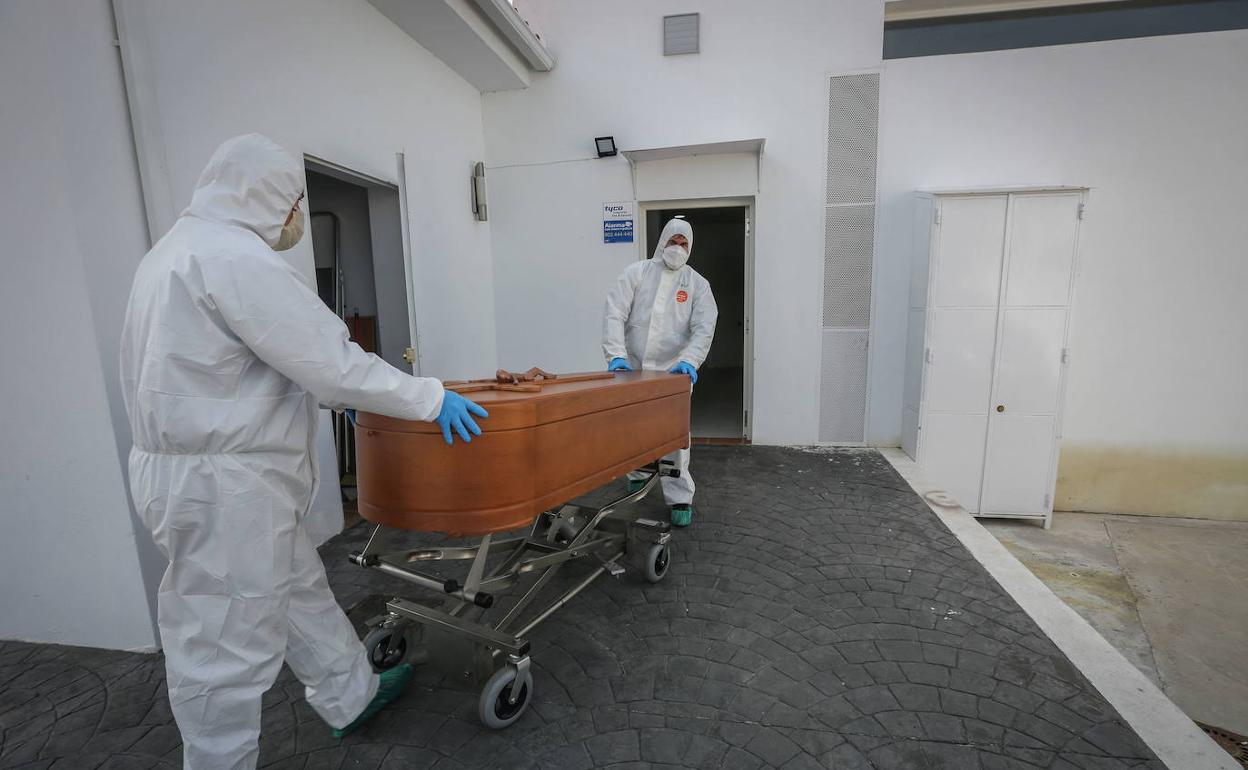 Empleados conducen el ataúd de una víctima de la covid en un tanatorio de Granada.