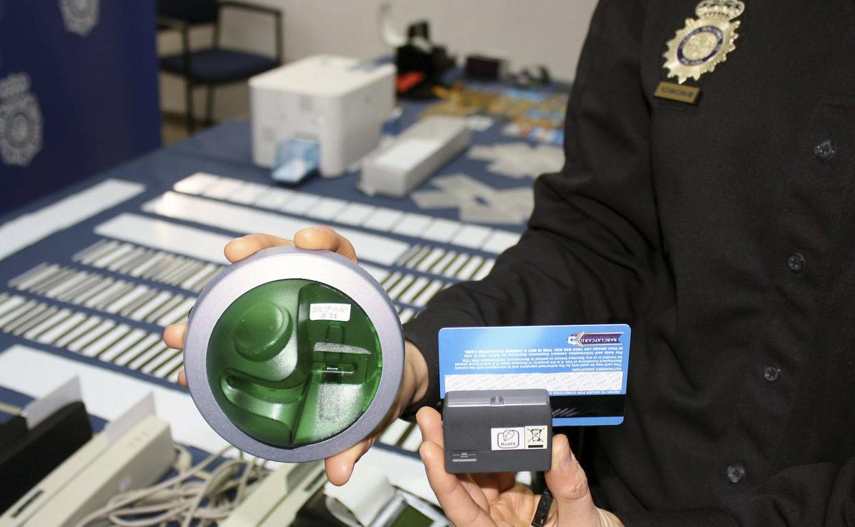 Un policía muestra un sistema para clonar tarjetas en cajeros.