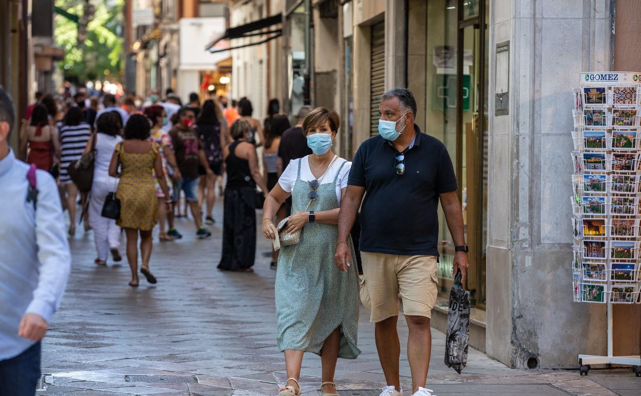 Ciudadanos con mascarillas, por el centro de Granada.