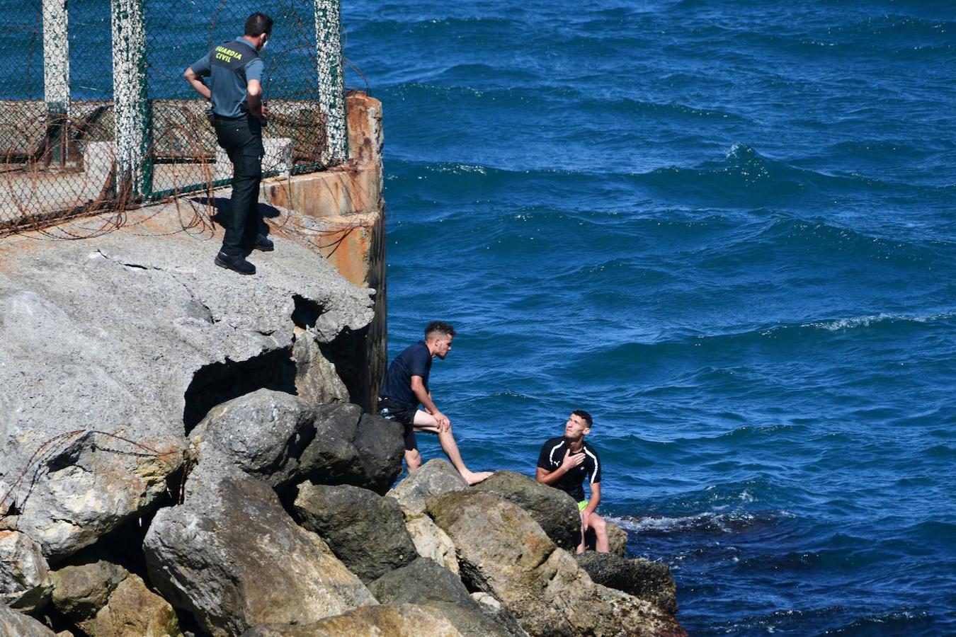 Un agente observa a dos de los migrantes mientras éstos se recuperan del esfuerzo. 