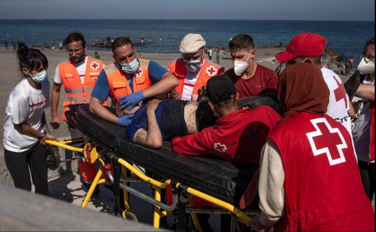 Efectivos de Cruz Roja trasladan en Ceuta a un migrante con signos de hipotermia. 