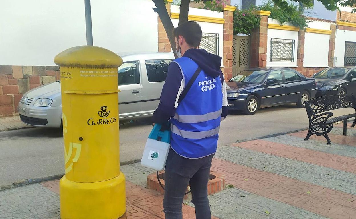 Un joven desinfecta un buzón de Correos en la plaza de España de Bailén. 