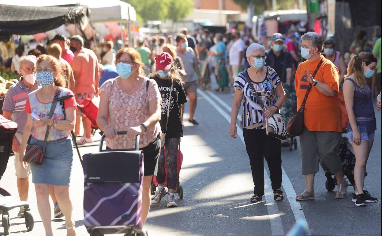 Gente paseando en un mercadillo con la mascarilla puesta. 