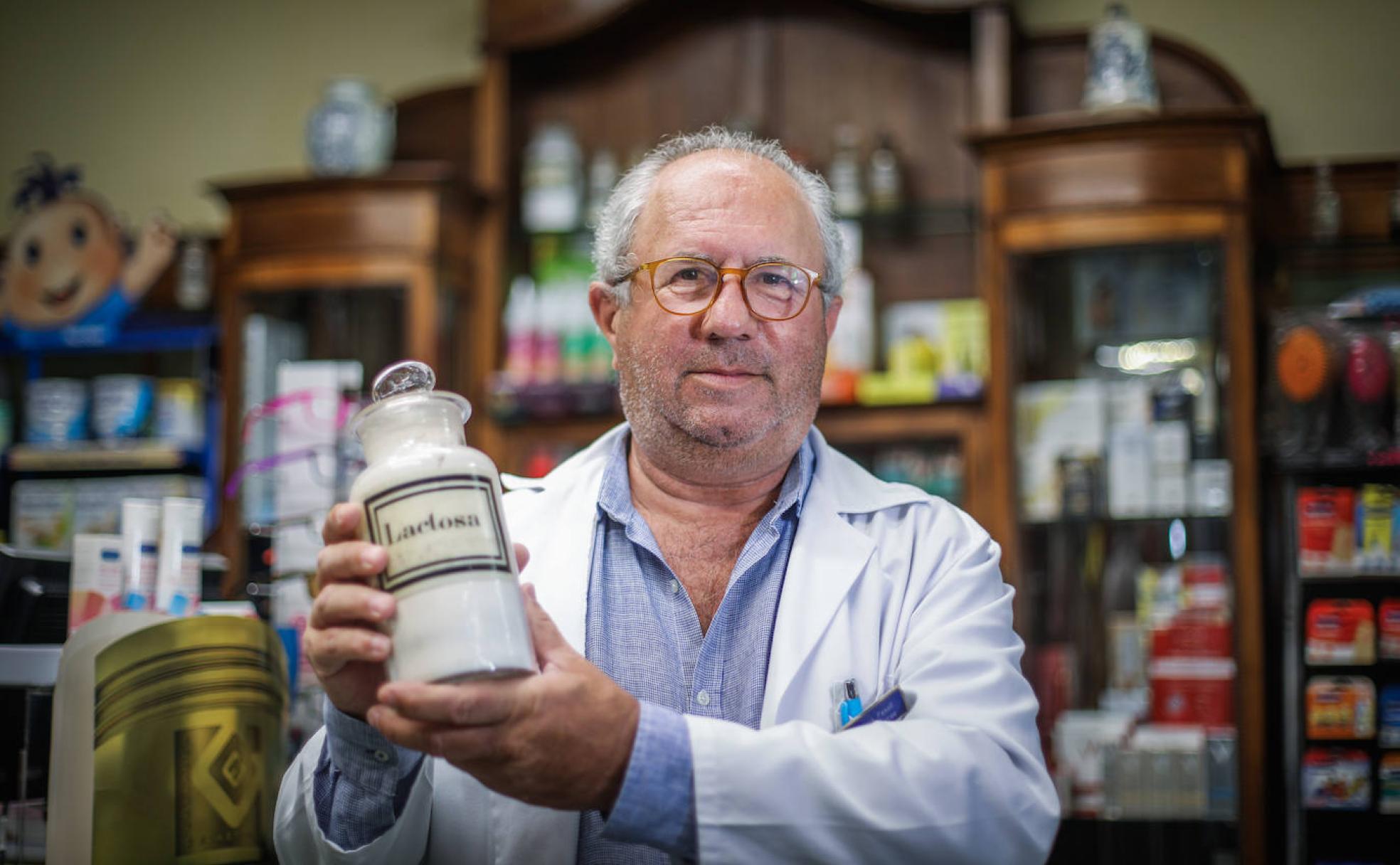 José Fenoll posa para IDEAL con su bata blanca y uno de los clásicos frascos de farmacia que tiene expuestos en su botica. 