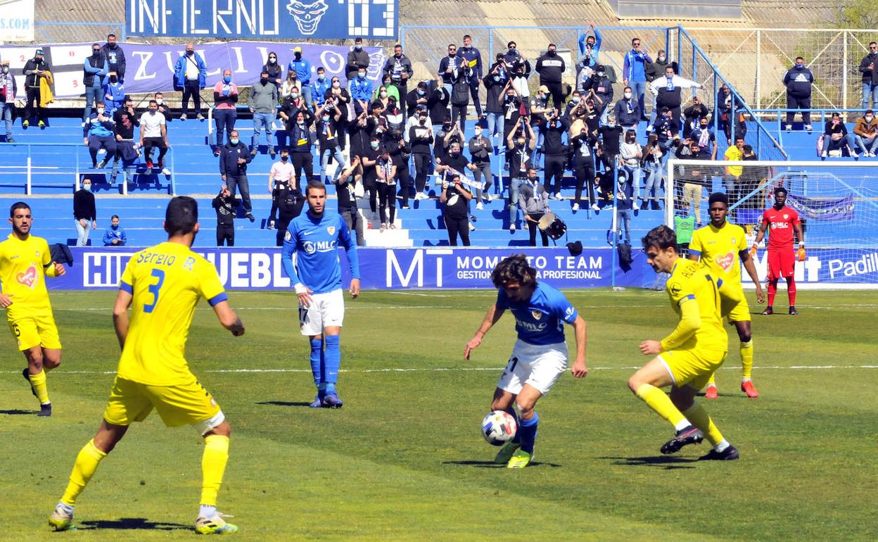 Rubén con el balón, al fondo la Grada Animación de Linarejos. 