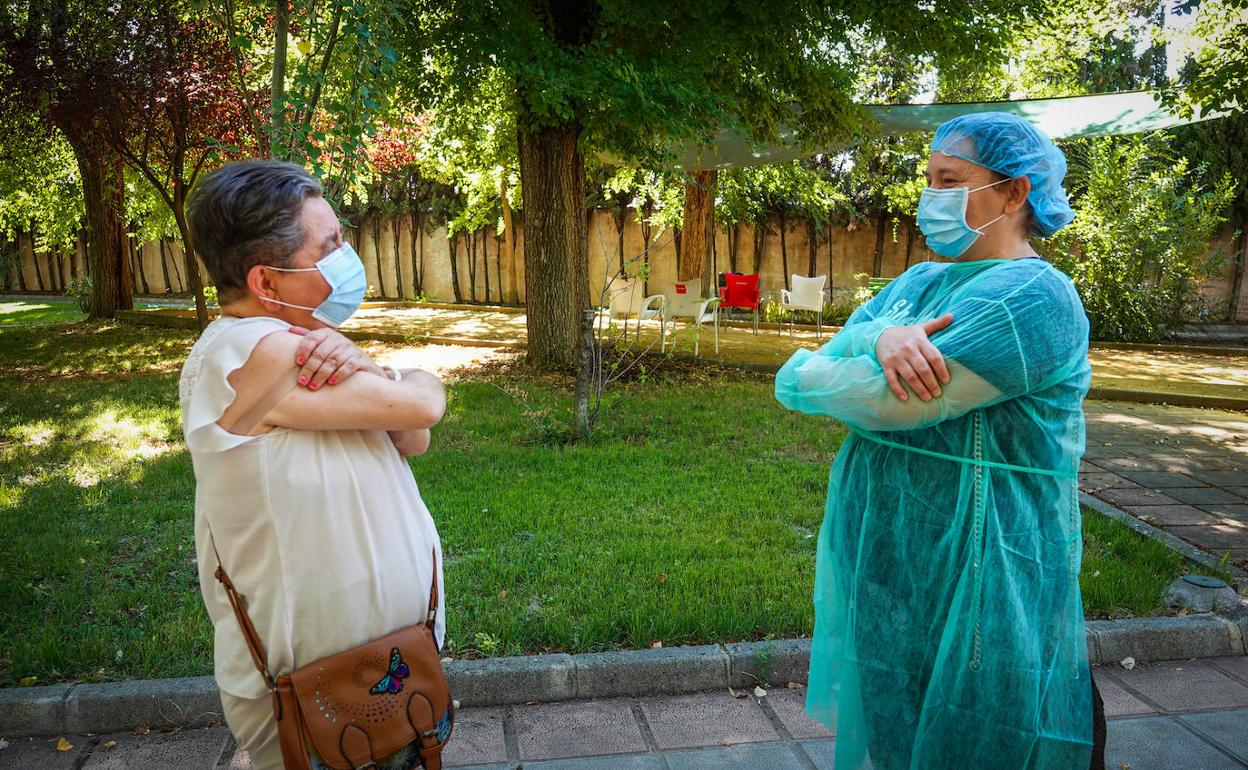 Una usuaria de las instalaciones que dependen de Diputación en Armilla saluda a distancia a su hermana, ataviada con un EPI, este jueves, en los exteriores del centro. 