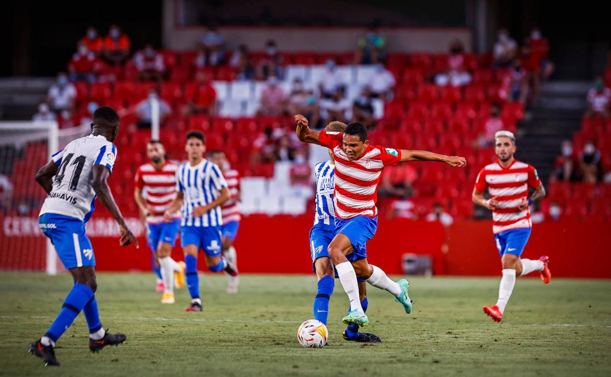 El rojiblanco Carlos Bacca avanza a pesar de la oposición de un rival malaguista durante el Trofeo Ciudad de Granada. 