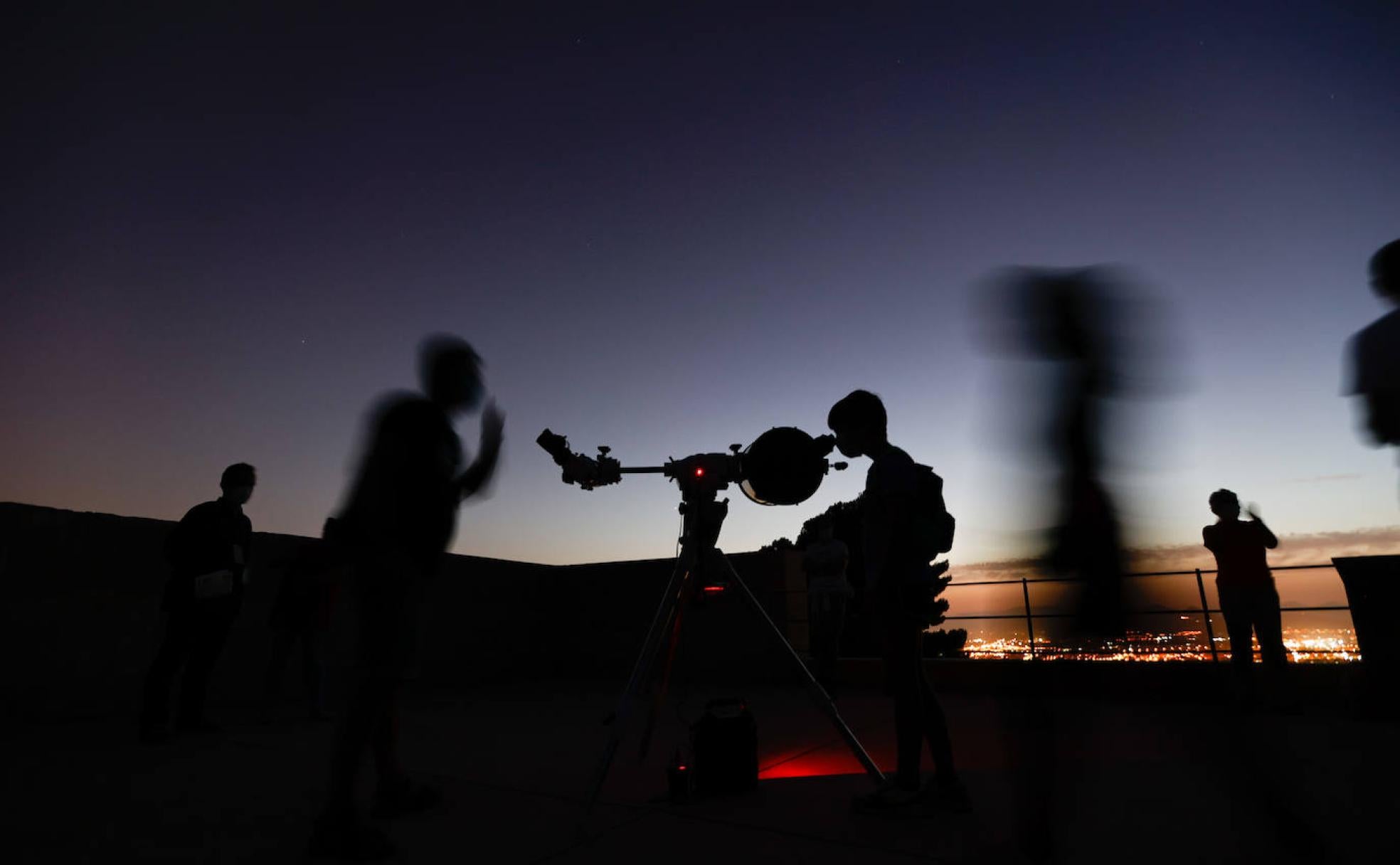 Asistentes a la sesión astronómica en la Silla del Moro observan el firmamento con Granada al fondo. 