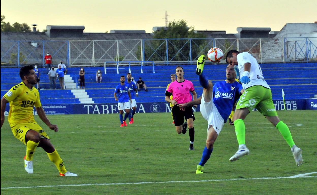 El meta del UCAMMurcia saliendo a despejar con la cabeza un balón que intenta controlar el delantero Etxaniz. 