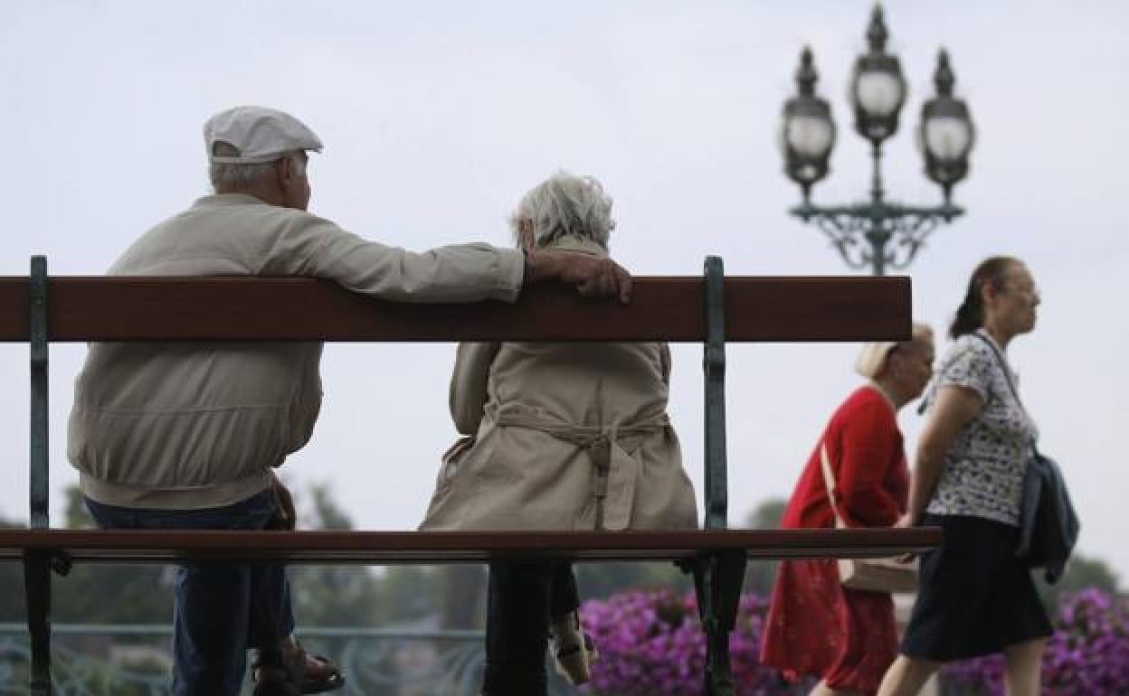 Una pareja de jubilados sentados en un banco.