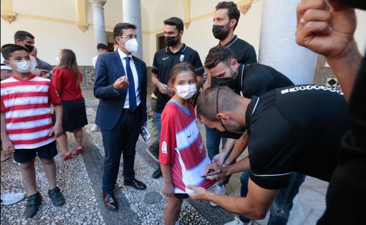 Víctor Díaz y Quini firman la camiseta a una joven seguidoar del equipo durante la recepción mientras el alcalde Paco Cuenca conversa con Jorge Molina y Germán Sánchez. 