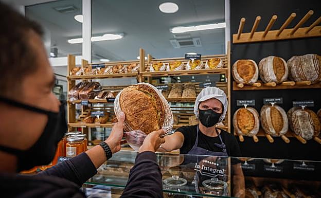 Ester vende a uno de sus clientes una hogaza de sus panes de masa madre con 24 horas de fermentación.