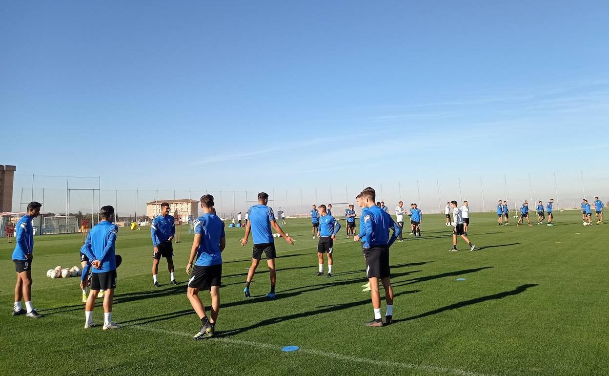 El rondo de jugadores del filial, en primer plano, con dos de la primera plantilla al fondo. 