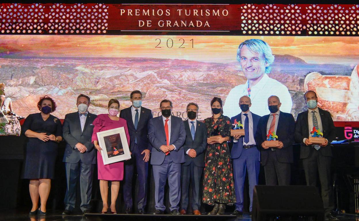 Los premiados posan sobre el escenario del Teatro Dengra de Baza junto a las autoridades políticas, con una imagen de Jesús Calleja de fondo.