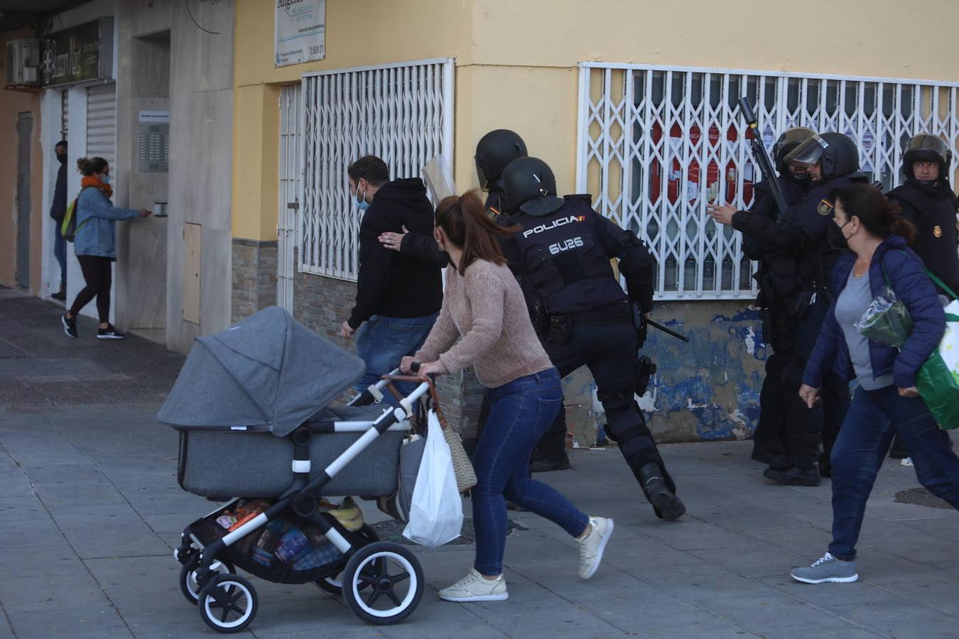 Una mujer corre con su hijo en una de las calles donde se han vivido los enfrentamientos entre los manifestantes y la Policía